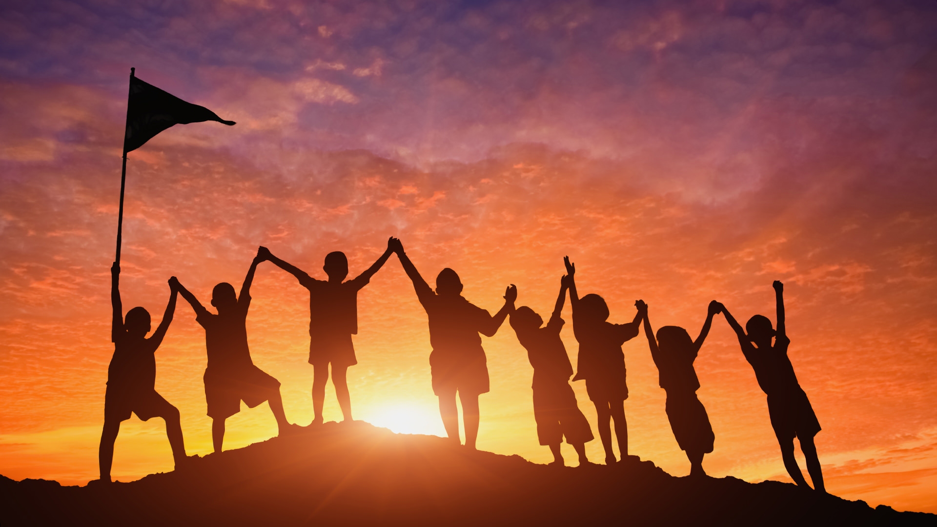 children raising flag at the top of a mountain